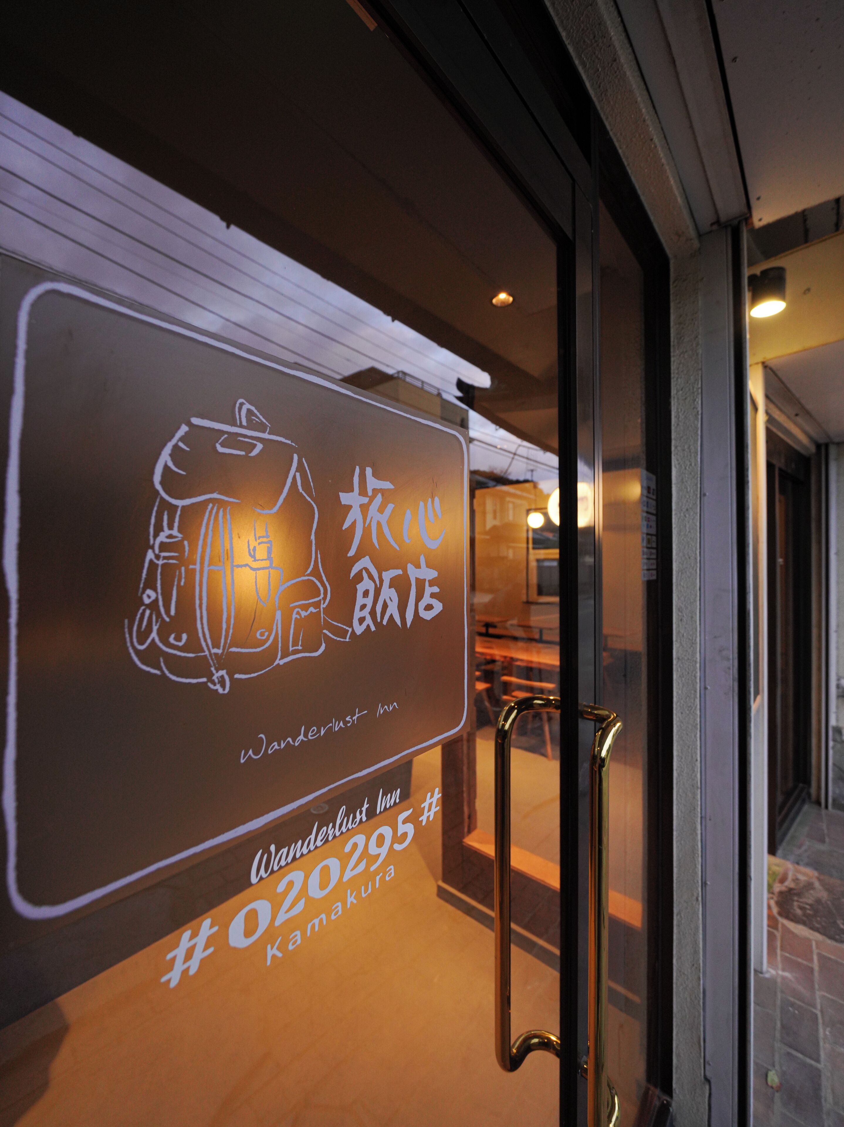 A sign with a bear illustration and text for Wanderlust Inn #020295 Kamakura.
