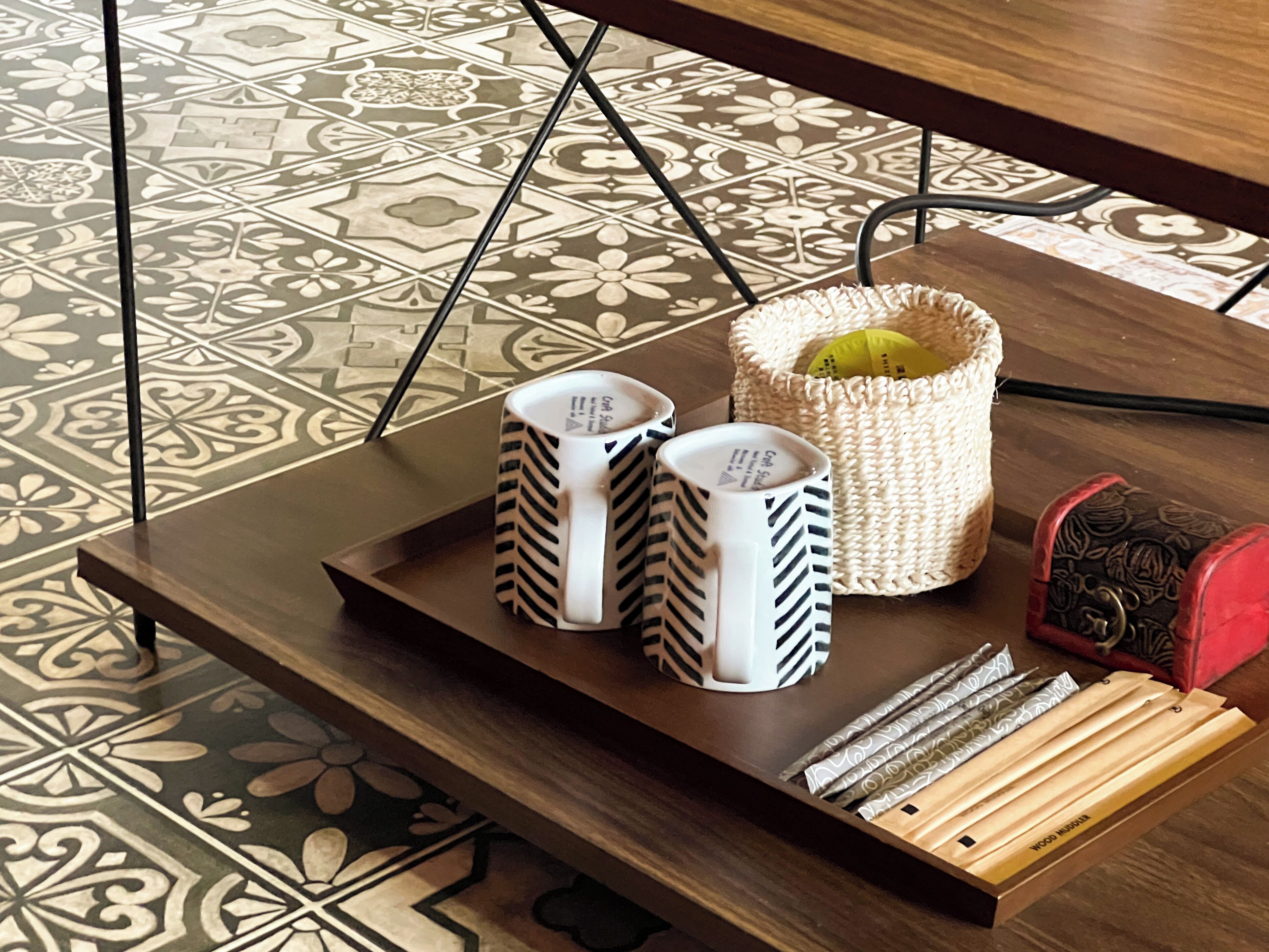 A tray with two mugs, a woven basket, and a set of wooden blocks on a table.