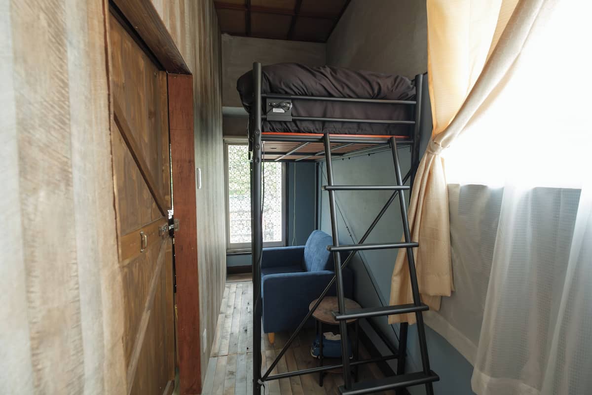 Una habitación pequeña con una litera, una silla y una escalera.