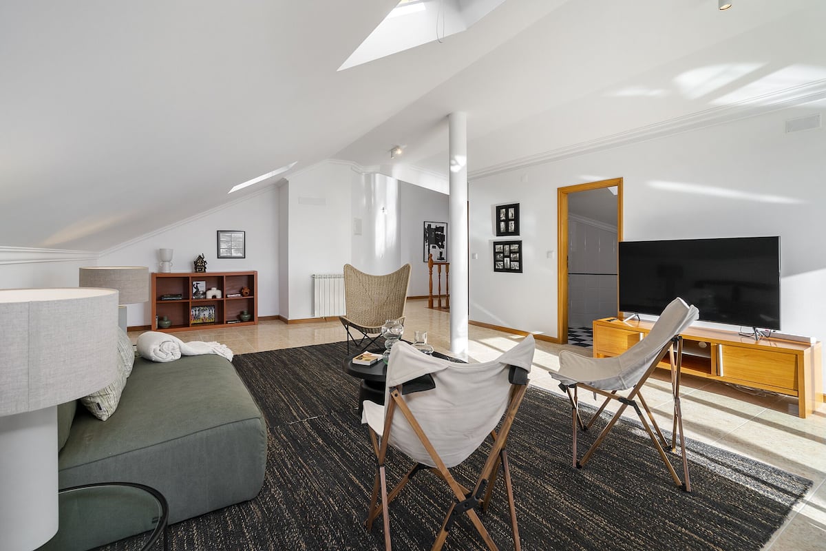 Una sala de estar moderna con techo alto, un sofá, una mesa de centro, un televisor y un mueble de madera.