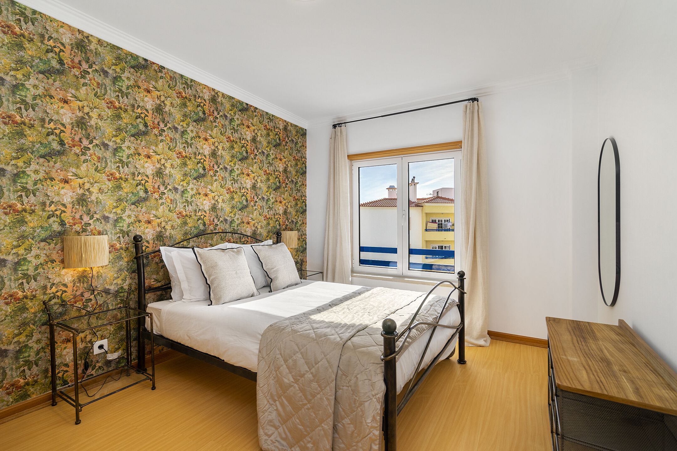A bedroom with a bed, a bedside table, a lamp, and a window with curtains.