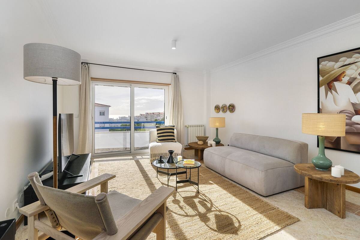 Una sala de estar moderna con sofá, sillón, mesa de centro y lámpara de pie.