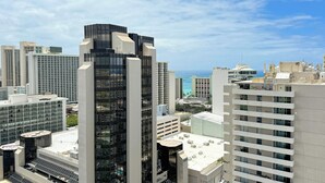 A high-rise building with a modern architectural design, featuring a prominent glass facade and a rooftop terrace. - Great Partial Ocean View! Full Kitchen, Free Parking, Pool! Heart of Waikiki! (Honolulu)