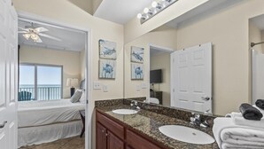 Une salle de bain d’hôtel avec un double lavabo, un ventilateur de plafond et des œuvres d’art accrochées aux murs.