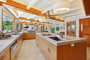 Une cuisine moderne dotée d’un grand îlot central, d’un four encastré et de nombreux plans de travail.