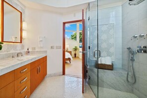 A modern bathroom with a glass shower, a marble sink, and wooden cabinets.
