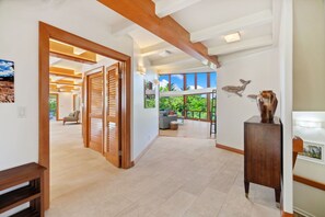 Un intérieur spacieux avec un plafond haut, des poutres en bois et une grande fenêtre donnant sur un paysage verdoyant.