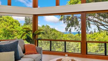 A spacious room with a large window offering a view of lush greenery and a distant landscape.