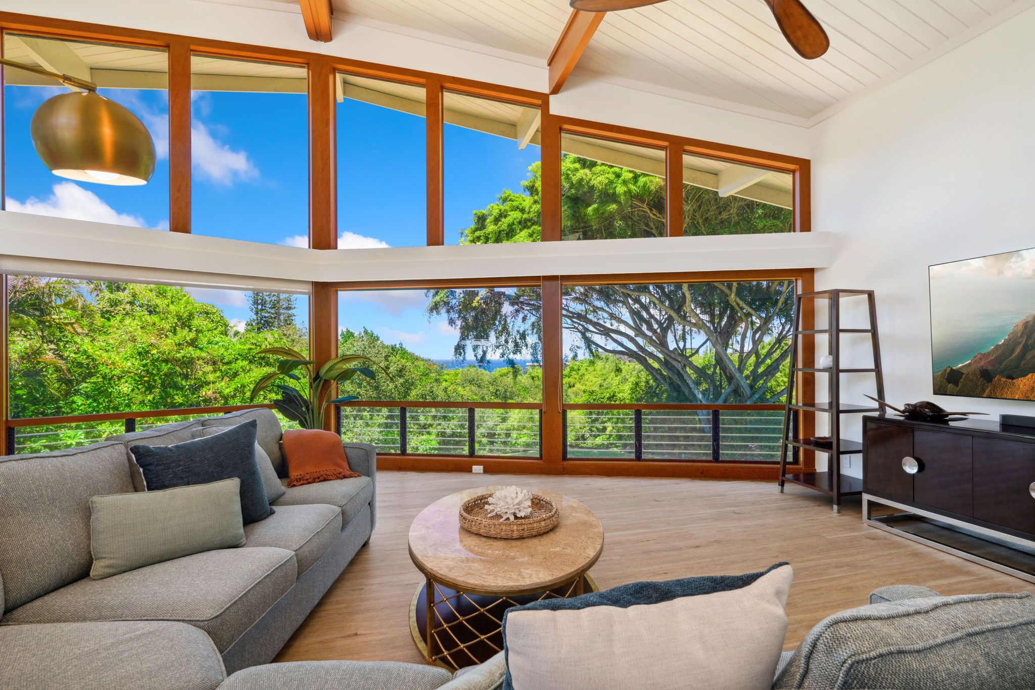 A spacious living room with a large sofa, a coffee table, and a TV on a wooden cabinet.