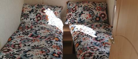 A small, enclosed sleeping area with two beds, each with floral-patterned bedding.