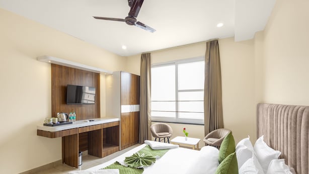 A hotel room with a bed, a desk, a chair, a TV, and a window with curtains. - Veda Inn By Casa Ekam (Yamkeshwar)
