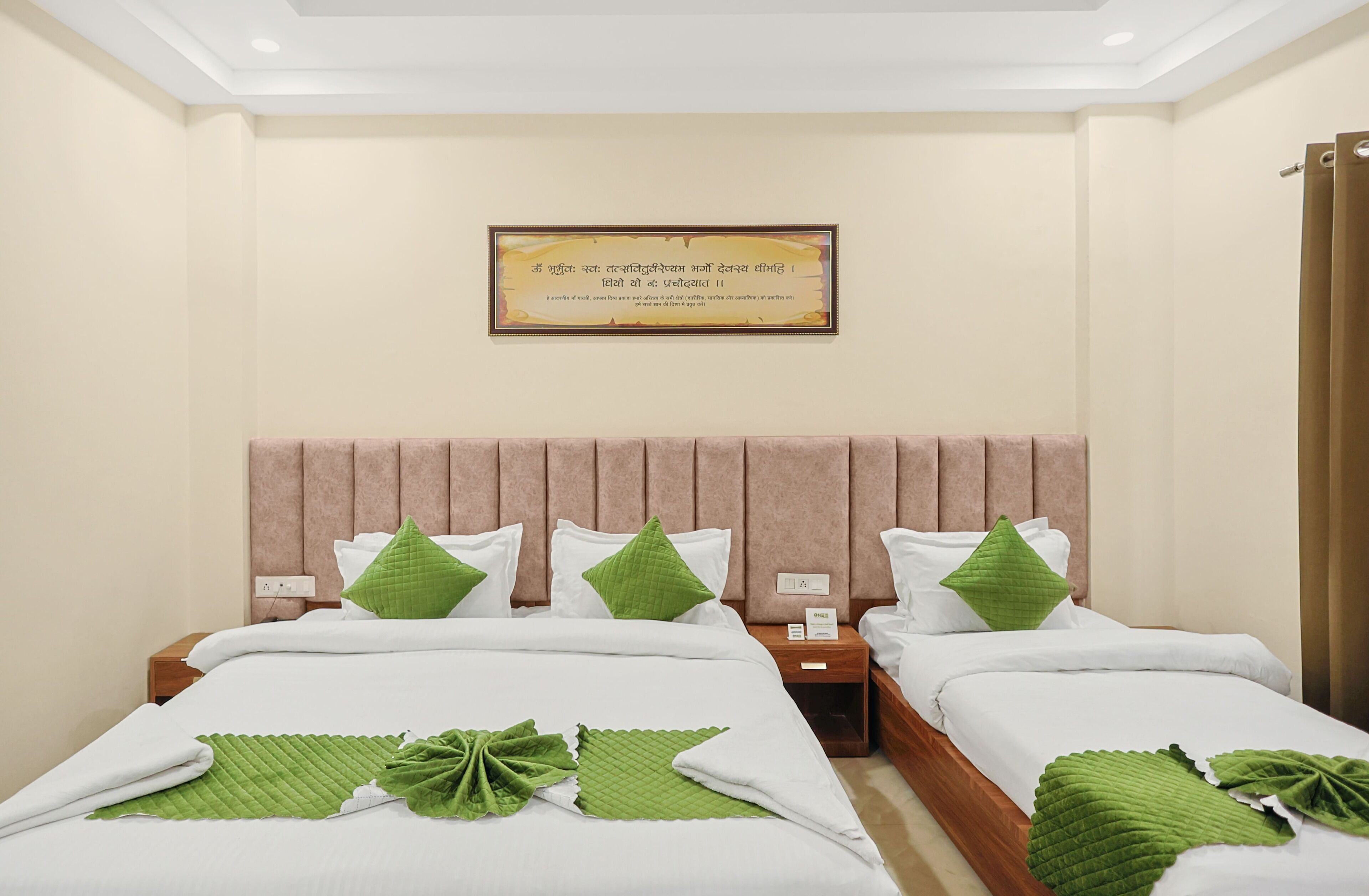 Une chambre d’hôtel avec deux lits, chacun étant équipé de draps blancs et d’oreillers verts. Un certificat encadré est accroché au mur, et une petite table porte un téléphone et une carte.