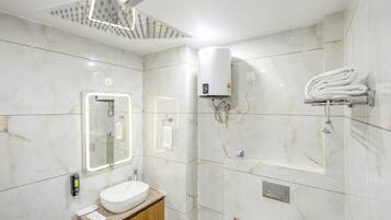A modern bathroom with a marble wall, a sink, a mirror, a towel rack, and a shower head.