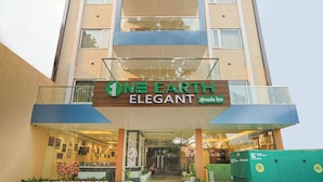 A hotel entrance with a sign reading "ONE EARTH ELEGANT" and a visible outdoor seating area with chairs and plants. - Veda Inn By Casa Ekam (Yamkeshwar)