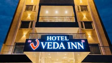 A hotel named VEDA INN with a prominent sign, multiple floors, and a well-lit entrance.