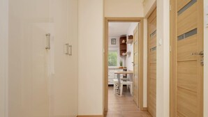 A hallway with a wooden floor, white walls, and a door leading to a room with a window. - Spacious Apartment | 2 Bedrooms and Balcony close to the Center (Warszawa)