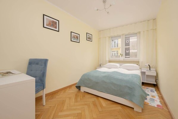 Een slaapkamer met een bed, een stoel, een bureau en een raam.