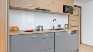 A modern kitchen with grey cabinets, a wooden countertop, a microwave, a kettle, and a sink.