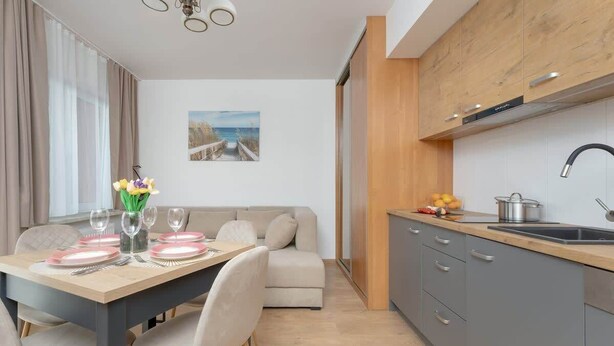 A modern kitchen with grey cabinets, a wooden countertop, and a stainless steel sink.