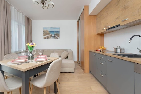 A modern kitchen with grey cabinets, a wooden countertop, and a stainless steel sink.