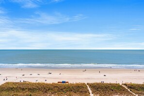 Een strand met een heldere lucht, rustige zee en een pad naar het strand.