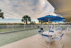 An outdoor patio with a white fence, palm trees, and a view of the beach. - Recently updated oceanfront unit, wonderful views + Free Attraction Tickets! (North Myrtle Beach)