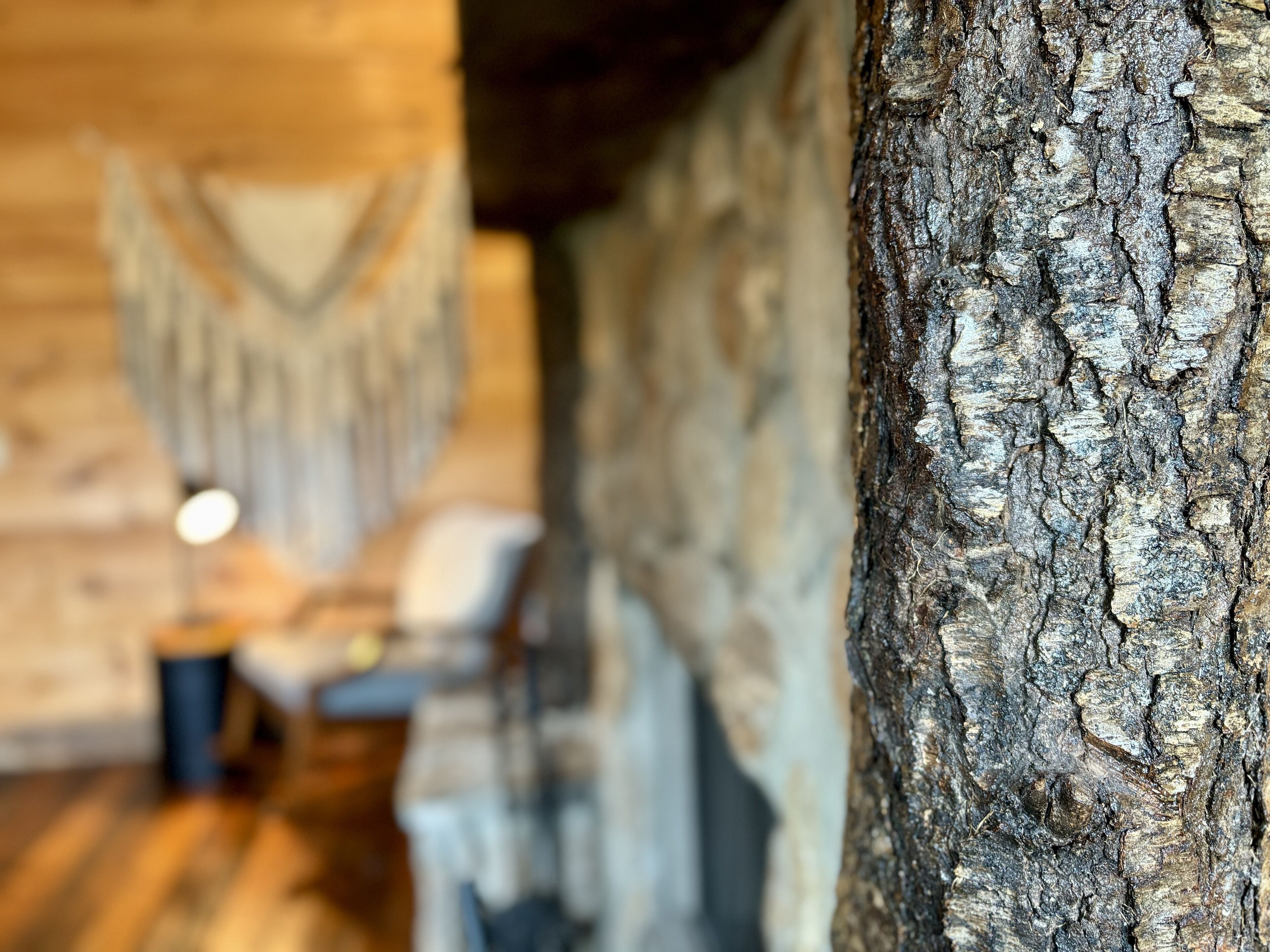 A rustic interior with exposed wooden beams, a stone wall, and a wooden floor.