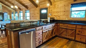 Una cocina de madera con lavavajillas integrado, armarios de madera y un amplio ventanal.