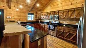 Una cocina rústica con paredes de madera, una isla central y electrodomésticos modernos.