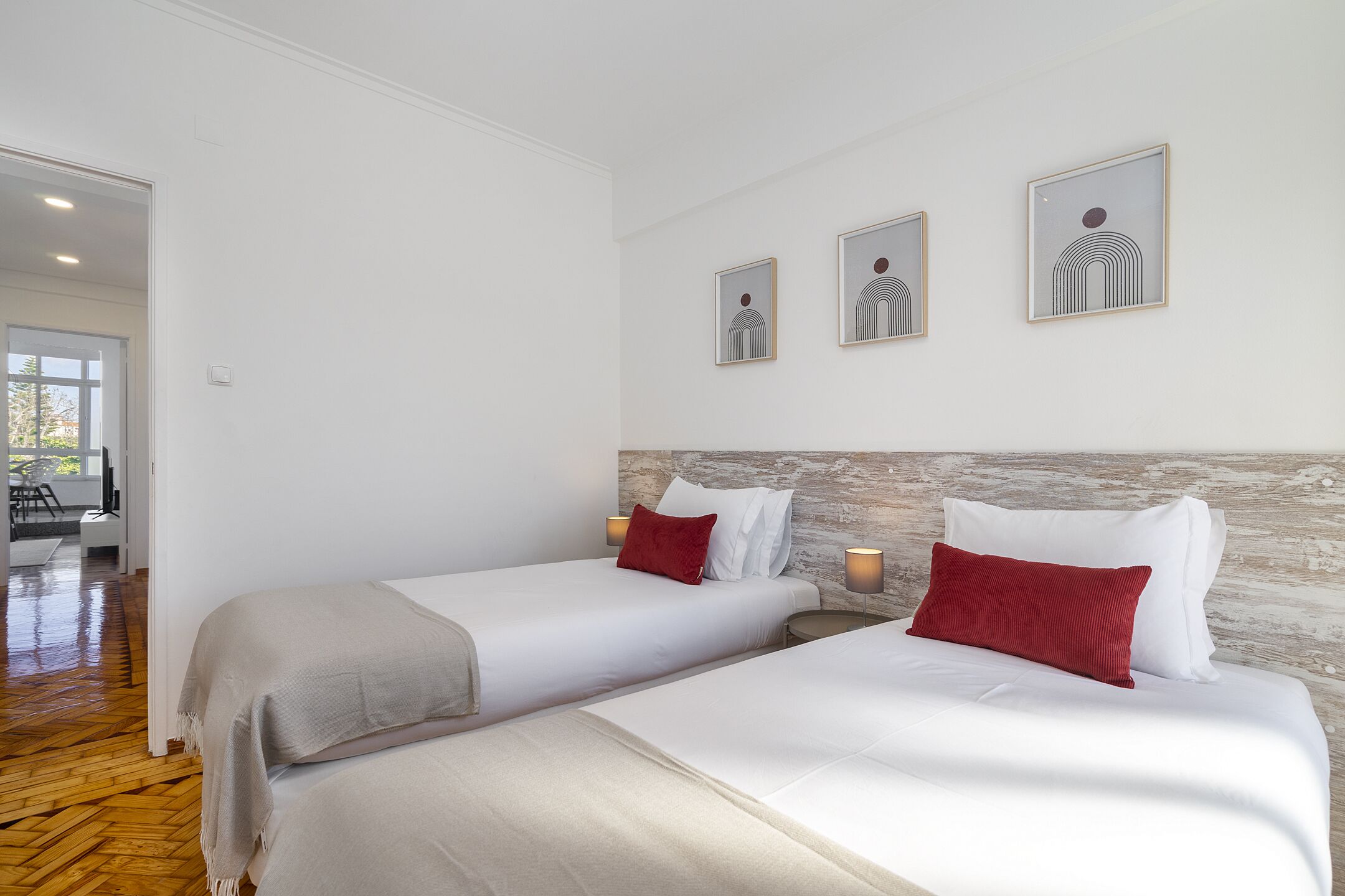 Habitación de hotel con dos camas, suelo de madera, pared de acento de piedra y obras de arte enmarcadas en la pared.