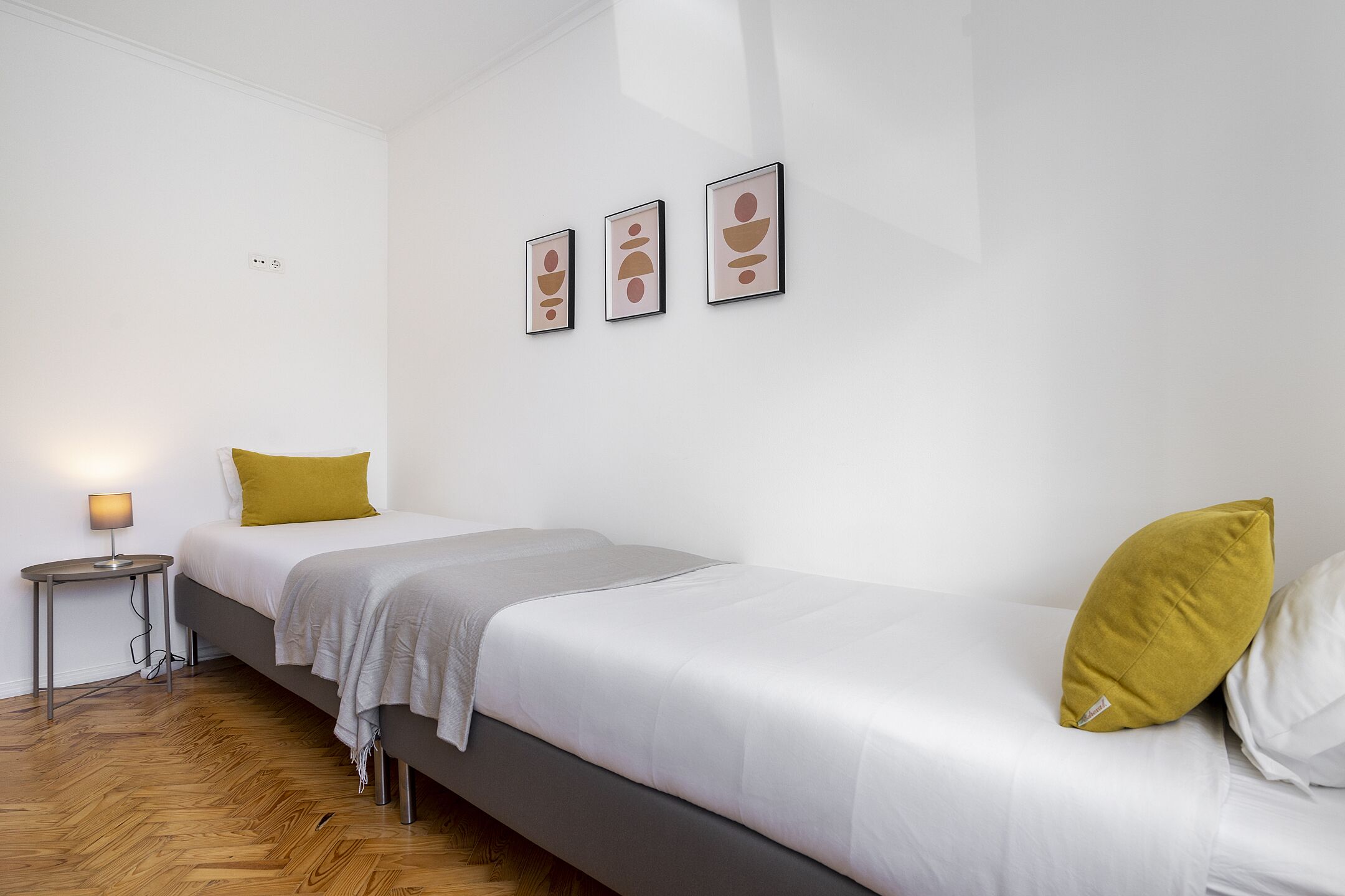 A modern bedroom with a bed, bedside tables, and wall-mounted artwork.
