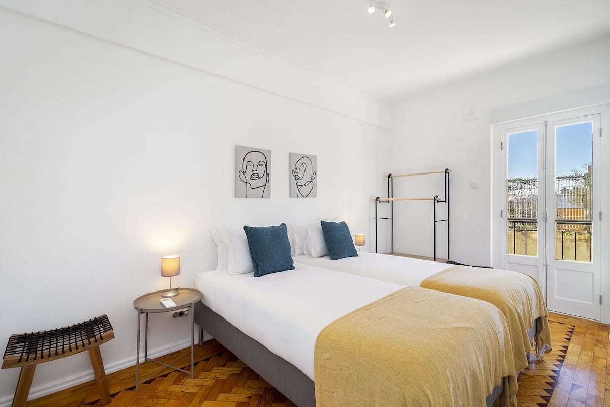 Habitación de hotel con cama, una mesita de noche con lámpara, una silla y ventana con vistas.