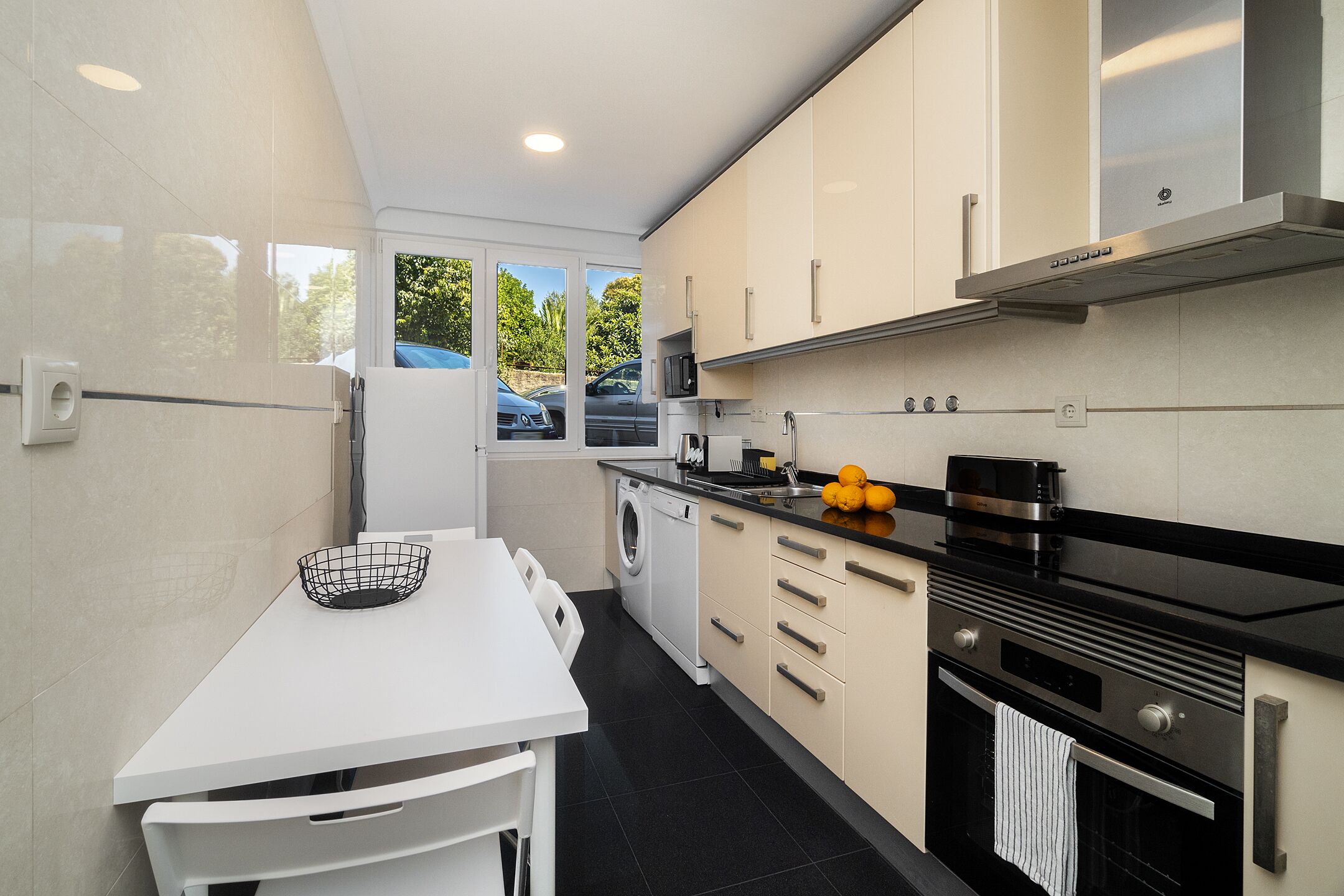 A modern kitchen with white cabinets, a black countertop, and a built-in oven.
