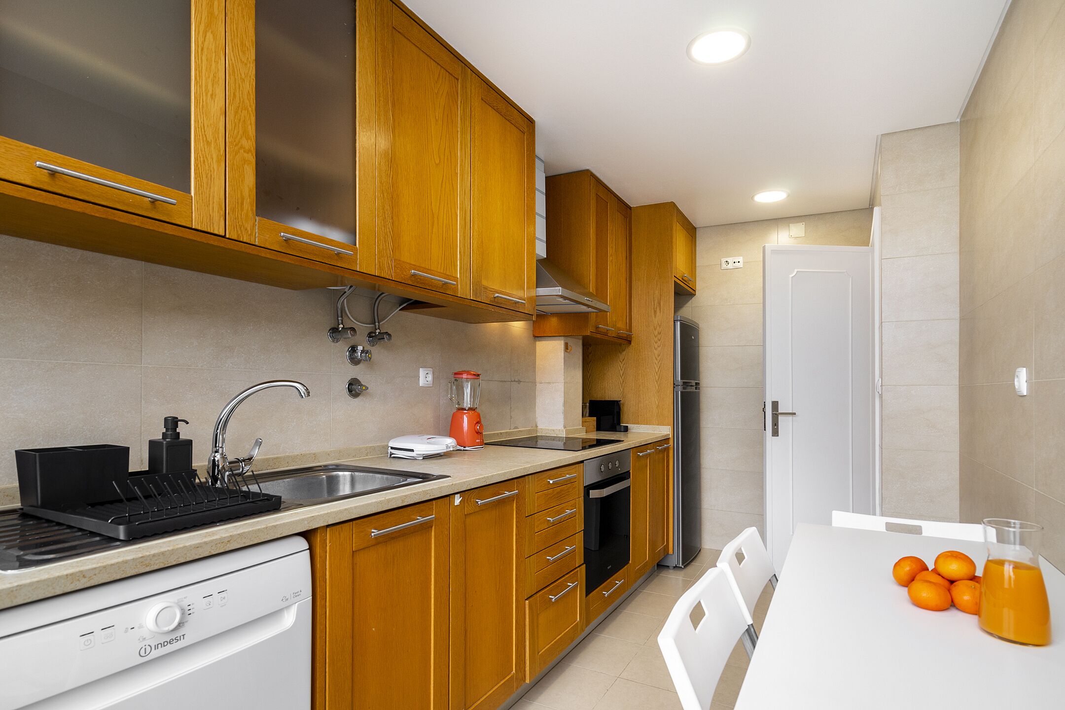 A modern kitchen with wooden cabinets, a dishwasher, a stove, and a sink.