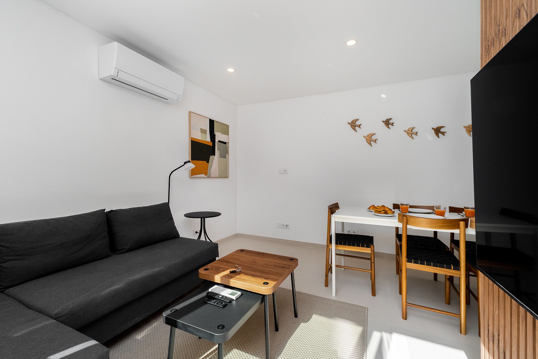 Una sala de estar moderna con sofá, mesa de centro y comedor con sillas y una mesa.