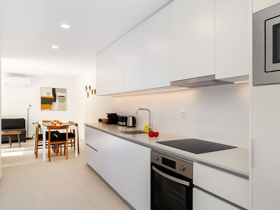 A modern kitchen with white cabinetry, a black countertop, and stainless steel appliances.
