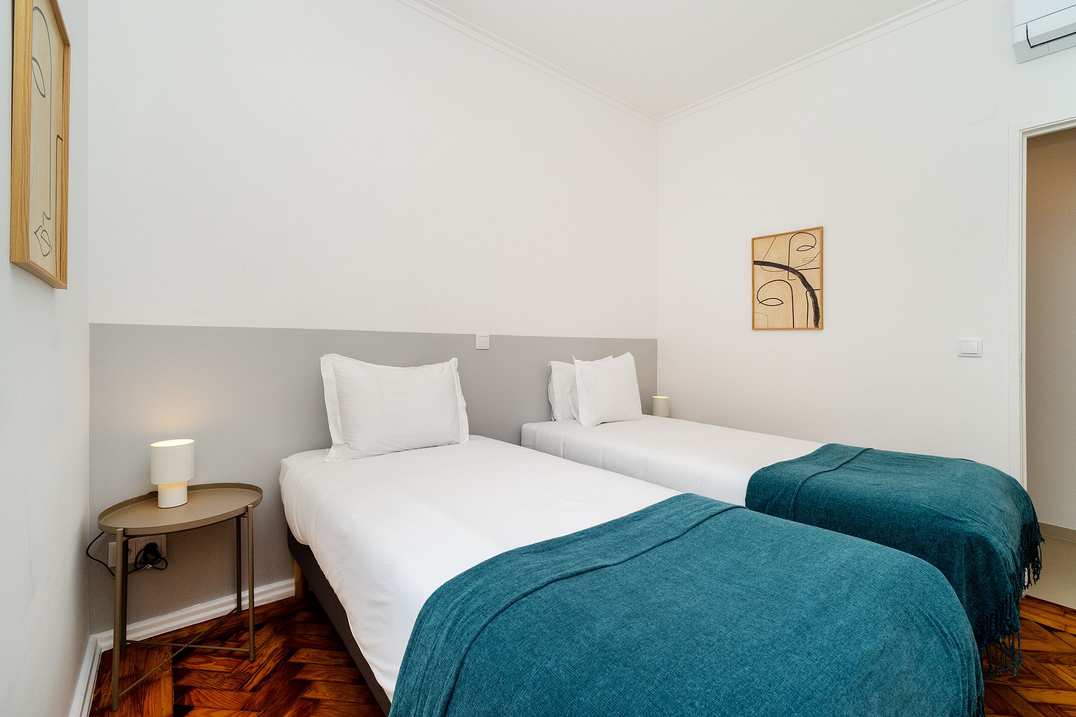 Une chambre d’hôtel avec deux lits simples, une table de chevet avec une lampe et une œuvre d’art accrochée au mur.
