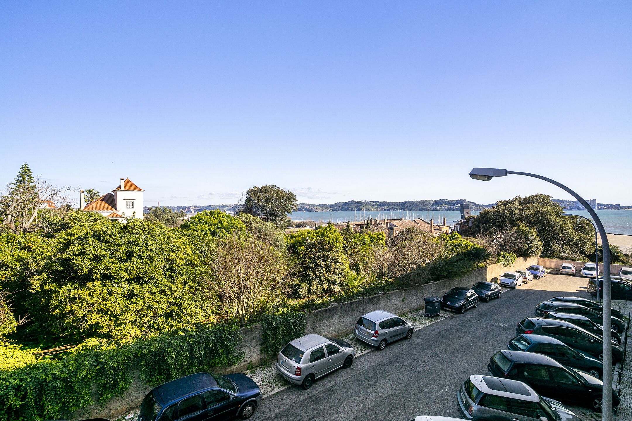 A parking lot with cars and a view of a coastal area with buildings and trees.