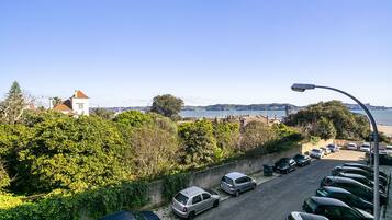 A parking lot with cars and a view of a coastal area with buildings and trees.