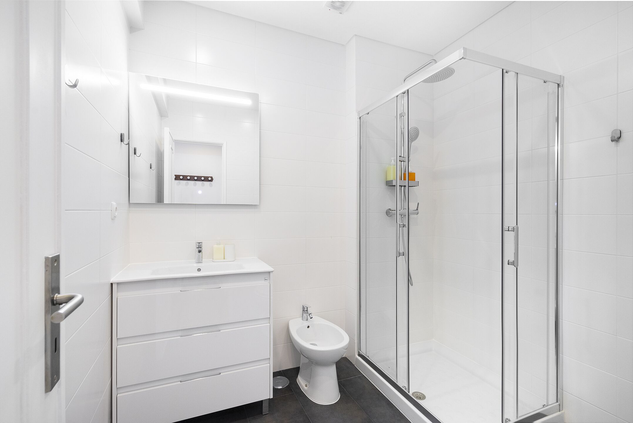 Un baño moderno con cabina de ducha de vidrio, un lavamanos blanco y un bidé.