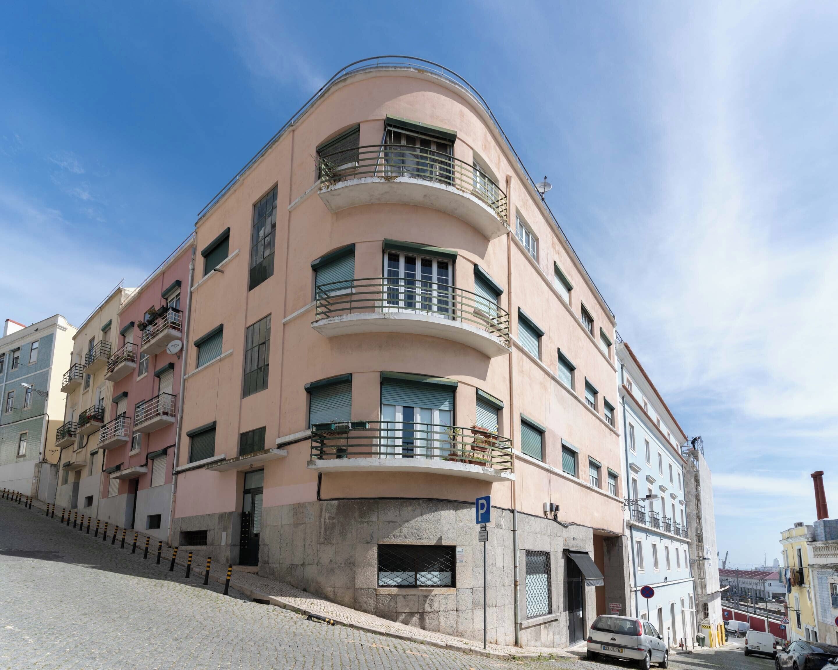 Un edificio de varios pisos con balcones, un letrero de estacionamiento y una calle adoquinada.