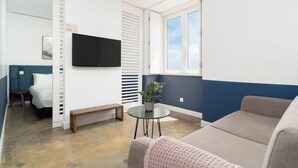 Una sala de estar moderna con un televisor de pantalla plana, una planta en maceta, un banco y un sofá.