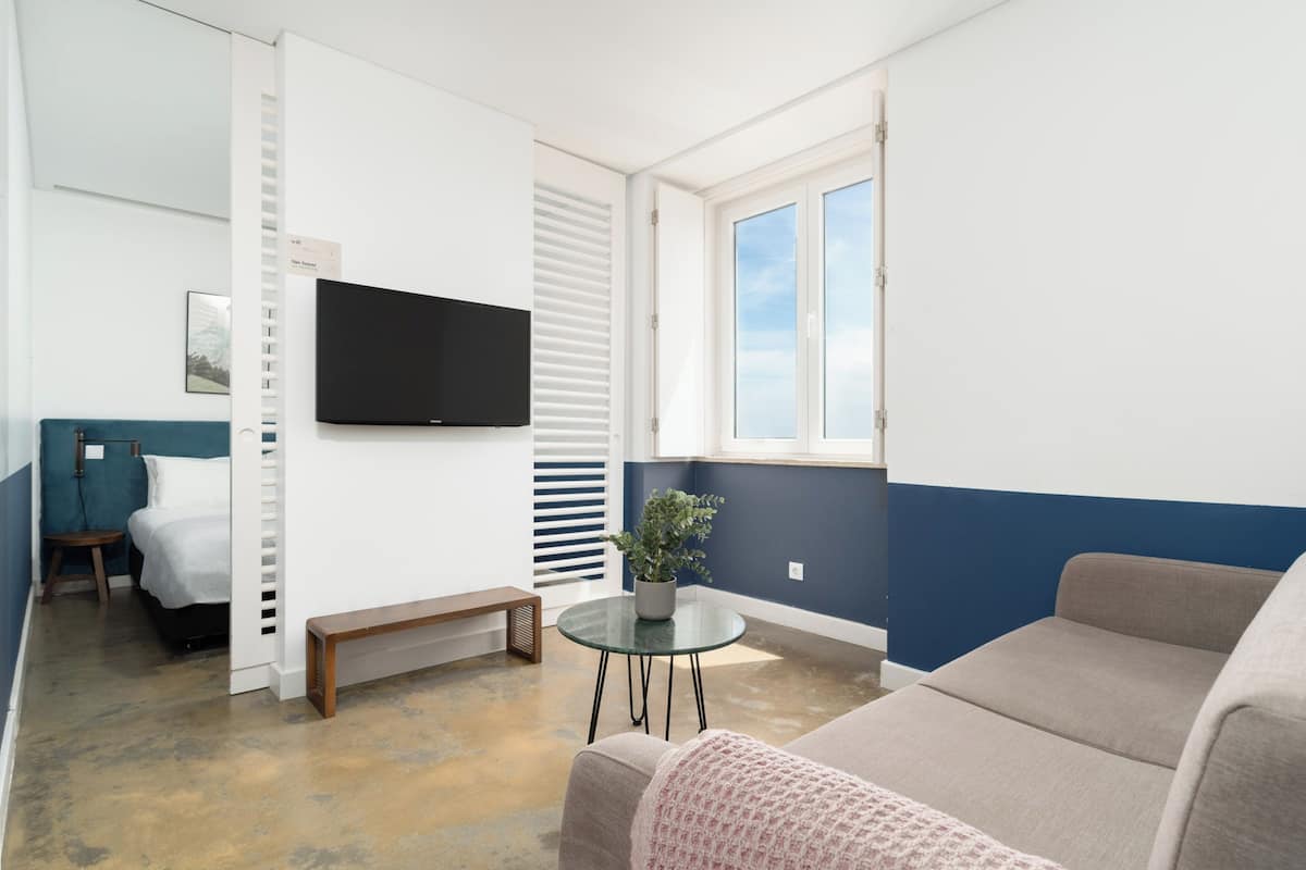 Un salon moderne avec un téléviseur à écran plat, une plante en pot, un banc et un canapé.