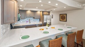 A modern kitchen with a central island, built-in appliances, and recessed ceiling lighting.