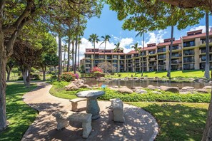 A resort with a landscaped garden, a pond, and a building with multiple balconies. - Kamaole Sands 6-101 Completely Renovated Garden View Inner Court Central AC! (Kihei)