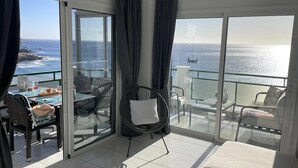 En balkon med havudsigt, et spisebord med stole og en sofa.