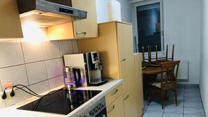 Una cocina compacta con estufa a gas, cafetera y comedor con mesa y sillas.