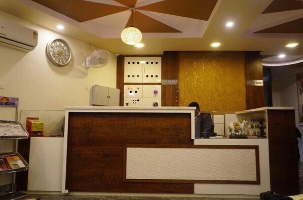 A reception area with a wooden reception desk, a clock, and a wall-mounted air conditioning unit.