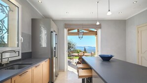 A modern kitchen with a long countertop, wooden cabinets, and a view of the outdoors.