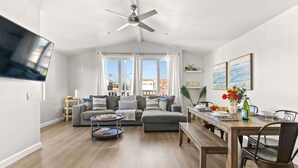 A spacious living room with a large flat-screen TV, a ceiling fan, and a dining area with a wooden table and chairs. - 9 Bedrooms-7 Bath-2 Kitchens-Parking-Sleeps 22! (San Diego)